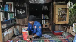 Iwan saat merapikan buku yang telah dibaca oleh anak-anak di perpustakaan Bale Buku Meleduk (Membaca Literasi Dukuh) 75 di Jalan Dukuh V, Kelurahan Dukuh, Kecamatan Kramat Jati, Jakarta Timur, Rabu (24/8/2022). Meski tidak terlalu besar, perpustakaan ini memiliki keunikan karena dibangun oleh Iwan dengan memanfaatkan barang-barang bekas yang didapat dari sekitar saat rutinitas sebagai PPSU. (merdeka.com/Iqbal S. Nugroho)