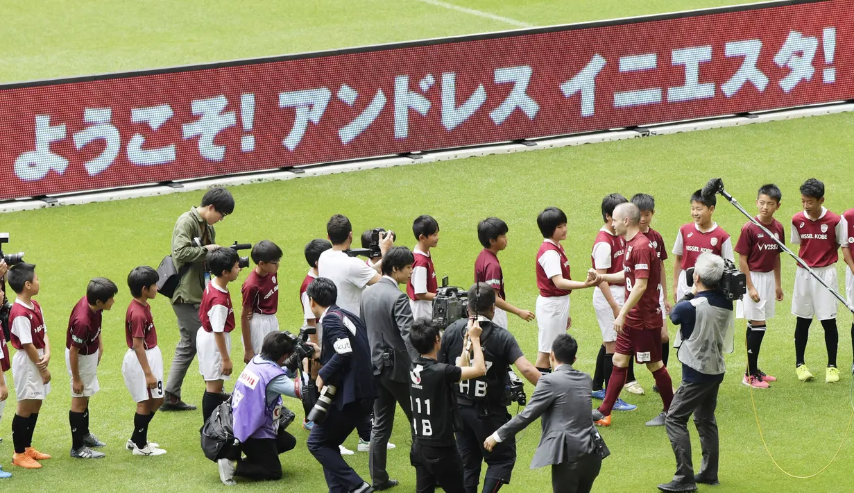 Pemain baru Vissel Kobe, Andres Iniesta menyalami anak-anak  sekolah sepak bola saat perkenalan di NOEVIR Stadium Kobe, Kobe, (26/5/2018). Iniesta dikontrak Vissel Kobe selama tiga tahun. (Yohei Nishimura/Kyodo News via AP)