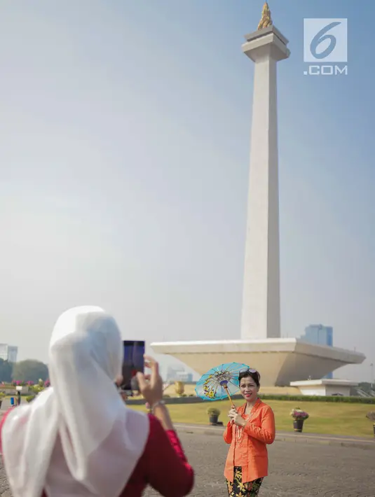 Seorang wanita mengenakan baju kebaya berpose mengikuti hari Gerakan Nasional kembali ke busana identitas Indonesia di Monas, Jakarta, Selasa (2/7/2019). Gerakan ini dinamakan sebagai Selasa Berkebaya untuk mengajak anak-anak muda tetap menjaga kelestarian busana kebaya. (Liputan6.com/Faizal Fanani)