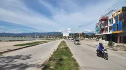 Kendaraan melintas di Pantai Talise (kiri) dan pusat bisnis Palu, Rabu (3/4). Bencana gempa dan tsunami yang melanda Palu pada 28 September 2018 lalu menewaskan 4.340 korban jiwa. (OLAGONDRONK/AFP)