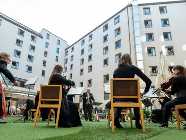 Para tamu Zeitgeist Hotel menikmati dari kamar mereka penampilan penyanyi Monika Medek dan Dagmar Dekanovsky serta orkestra Camerata Carnutum di Wina, Sabtu (30/5/2020). "Konser jendela" diadakan untuk merayakan pembukaan kembali hotel di Austria di tengah pandemi COVID-19. (JOE KLAMAR/AFP)