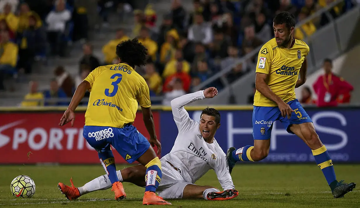 Penyerang Real Madrid, Cristiano Ronaldo, terjatuh akibat berebut bola dengan gelandang Las Palmas, Mauricio Lemos. Sementara bagi Las Palmas kekalahan ini membuat mereka turun ke peringkat 15. (Reuters/Juan Medina)