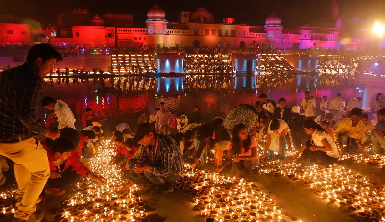 Masyarakat India menyalakan lampu dari tanah liat pada festival Diwali di tepi Sungai Sarayu, Ayodhya, Selasa (6/11). Kota di utara India itu memecahkan rekor dunia Guinness setelah menyalakan 300.150 lampu selama 45 menit. (AP/Rajesh Kumar Singh)