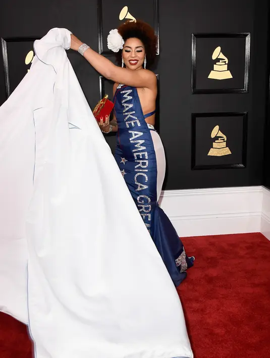 Penyanyi sekaligus komposer Joy Villa membuka jubah putih nya dan mengganti dengan gaun merah, putih dan biru berbordir slogan kampanye Donald Trump di karpet merah ajang Grammy Awards 2017 di Los Angeles, Minggu (13/2). (Frazer Harrison/Getty Images/AFP)