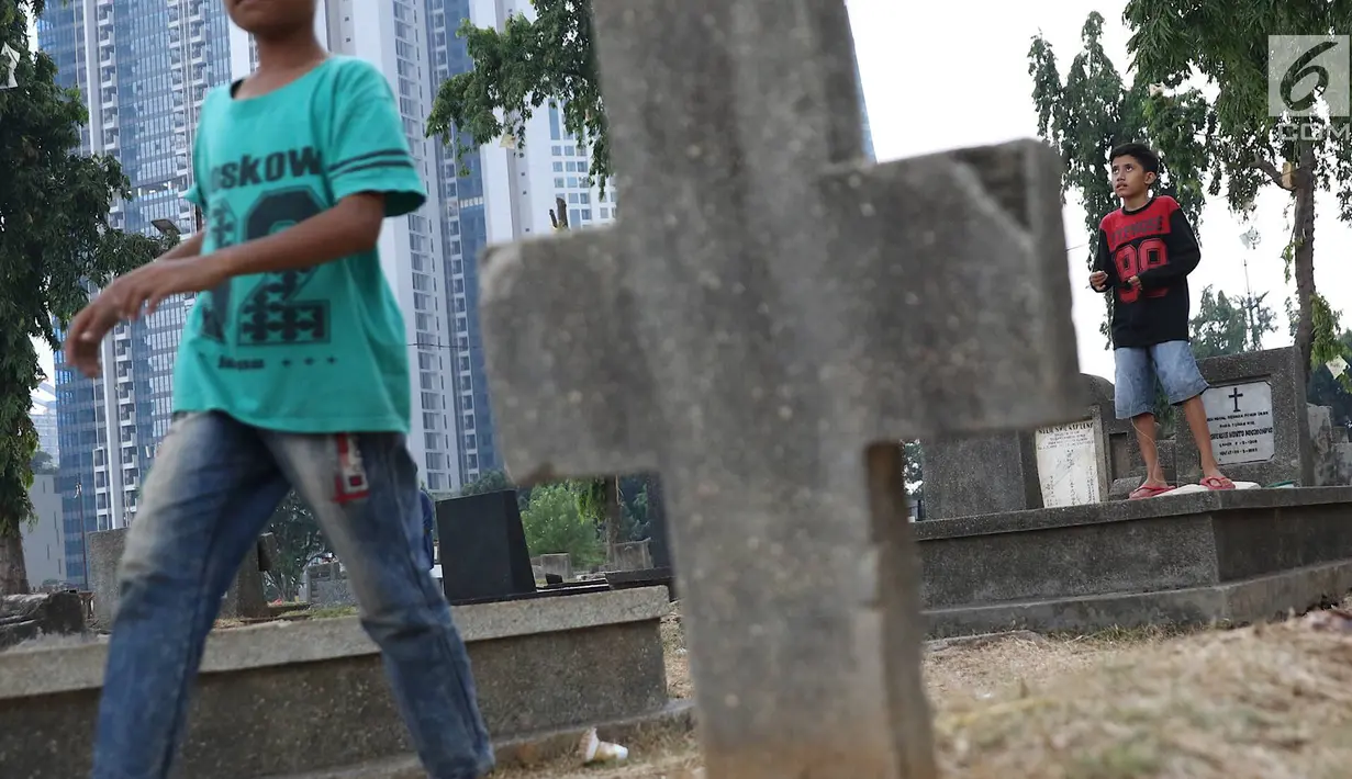 Anak-anak bermain layang-layang di TPU Menteng Pulo, Jakarta, Kamis (18/10). Padatnya pemukiman penduduk serta gedung bertingkat di kawasan tersebut menyebabkan anak-anak terpaksa bermain di tempat yang tidak semestinya. (Liputan6.com/Immanuel Antonius)