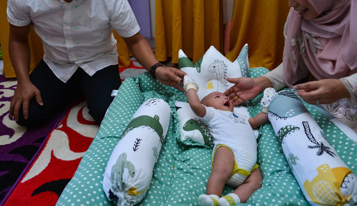 Tokoh adat dan agama mengendong bayi pada ritual 'peutron tanoh aneuk' (turun tanah anak) di Desa Alue Naga, Banda Aceh, Aceh, Senin (15/7/2019). Ritual turun tanah anak yang telah menjadi tradisi sakral bagi masyarakat Aceh yang dilaksanakan pada saat bayi berusia 44 hari. (CHAIDEER MAHYUDDIN/AFP)