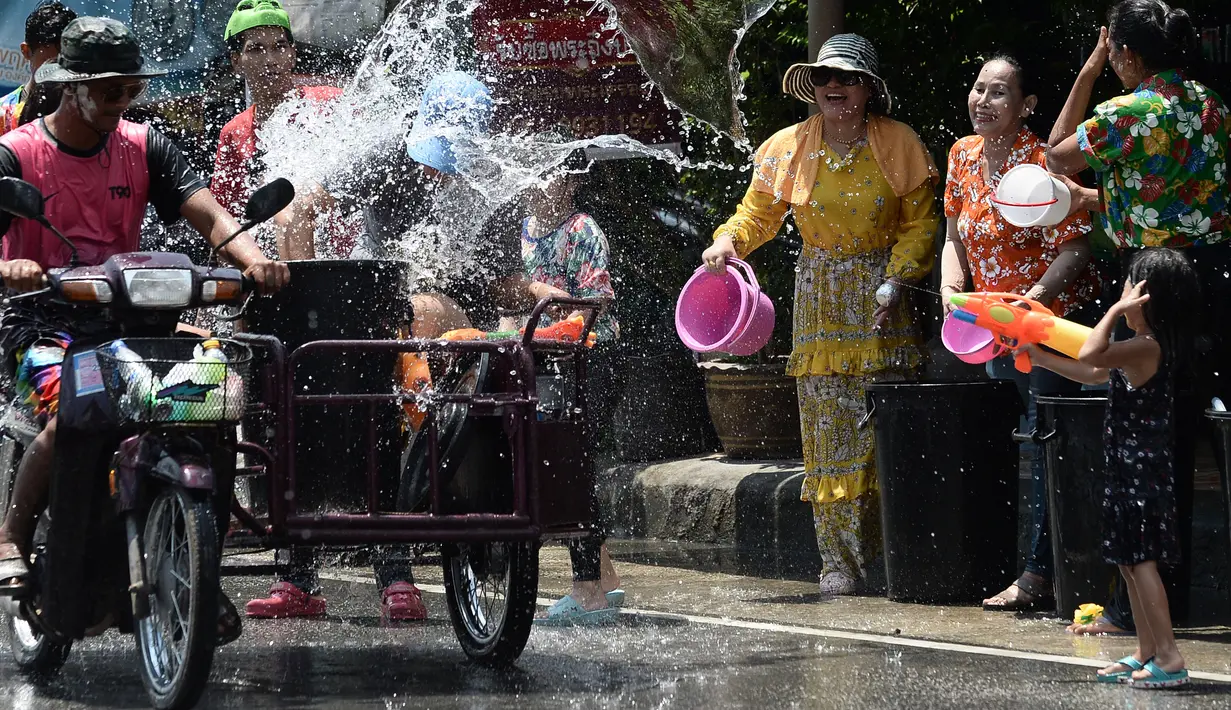 Warga menghujani pengendara sepeda motor dengan air saat merayakan Festival Songkran atau Tahun Baru Thailand di Narathiwat, Thailand, 13 April 2019. Festival ini rutin diselenggarakan setiap tanggal 13-15 April setiap tahunnya. (Madaree TOHLALA/AFP)