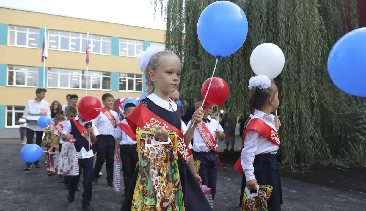Anak-anak kelas satu mengikuti upacara yang menandai dimulainya kelas di sebuah sekolah di Mariupol, daerah yang dikuasai oleh pasukan separatis yang didukung Rusia, Ukraina timur, Kamis (1/9/2022). Banyak sekolah Ukraina dibuka kembali pada 1 September untuk pertama kalinya sejak invasi Rusia dimulai pada 24 Februari lalu. (AP Photo)