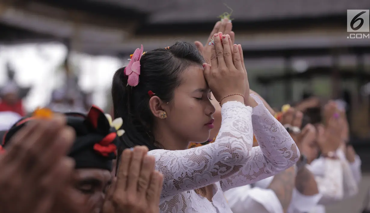 Seorang Umat Hindu berdoa dalam prosesi ritual tahunan Purnama Kapat di tengah aktivitas Gunung Agung pada level awas di Pura Besakih, Karangasem, Bali, Kamis (5/10). Ritual setahun sekali ini digelar setiap bulan purnama. (Liputan6.com/Gempur M Surya)