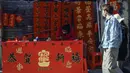Seorang kaligrafer menulis kuplet musim semi, semacam dekorasi Tahun Baru Imlek, jelang dimulainya Tahun Baru Imlek di sebuah kios di Foshan, Provinsi Guangdong, China, 18 Januari. Kuplet musim semi berasal dari era Shu (lebih dari seribu tahun yang lalu). (Giok Gao/AFP)