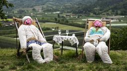Sebuah gambar pada 3 Mei 2022 menunjukkan dua orang-orangan sawah di ladang selama pekan raya tahunan di desa Castellar, Italia utara, dekat Cuneo. Warga menghias orang-orangan sawah layaknya manusia. Seperti mengenakan gaun, kemeja, topi, dan kaca mata lalu menempatkannya di kebun, halaman, ladang serta jalan.(MARCO BERTORELLO / AFP)
