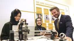 Mantan pemain sepak bola Inggris dan duta UNICEF, David Beckham bermain dengan robot yang dibuat oleh Tim Robotika Putri Afghanistan di Forum Doha di ibukota Qatar (27/3/2022). (Marwan Tahtah/Mofa/Doha Forum)