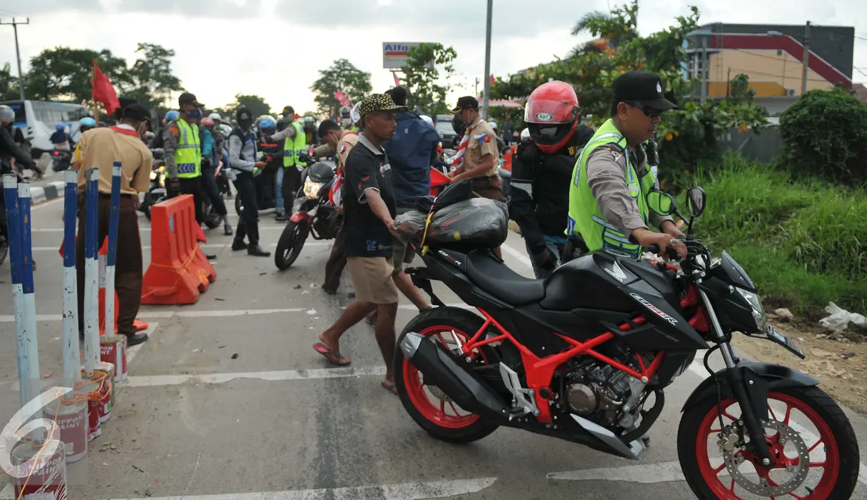 Petugas mencoba membantu menuntun motor akibat Kecelakaan yang terjadi di  jalan Lamaran, Karawang, Jawa Barat, Minggu (3/7). Kecelakaan kecil terjadi menimpa pemudik yang menggunakan sepeda motor di jalan Lamaran, Karawang. (Liputan6.com/Gempur M Surya)