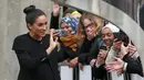 Duchess of Sussex, Meghan Markle seusai mengunjungi Association of Commonwealth Universities (ACU) di London, Kamis (31/1). Meghan tampil dalam balutan coat hitam rancangan Givenchy untuk membungkus dress dengan rok lipit. (Daniel LEAL-OLIVAS / AFP)