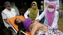 Petugas kesehatan saat memindahkan seorang wanita etnis Rohingya di tempat penampungan, Kuala Langsa, Aceh (25/5/2015). Pemerinta RI mengalokasikan bantuan sebesar Rp 2,3 Miliar untuk pengungsi Rohingya yang berada di Aceh. (Reuters/Darren Whiteside)