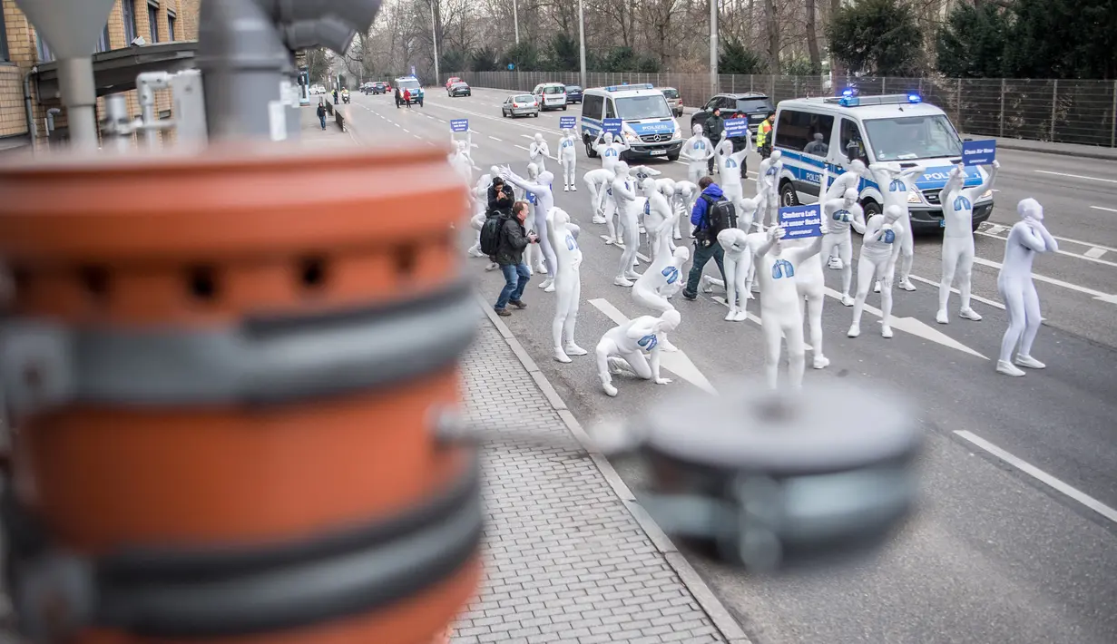 Aktivis dari Greenpeace mengenakan pakaian serba putih sambil membawa poster saat turun ke jalan untuk melakukan aksi di Stuttgart, Jerman (19/2). (Sebastian Gollnow/dpa/AFP)