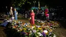 <p>Seorang wanita membaca pesan yang ditempatkan di antara karangan bunga untuk Ratu Elizabeth II di Green Park, dekat Istana Buckingham di London, Senin (12/9/2022). Sebelum menjabat Ratu Inggris, Elizabeth menerima pendidikan di rumah melalui guru pribadinya yang bernama Henry Marten. (AP Photo/Markus Schreiber)</p>