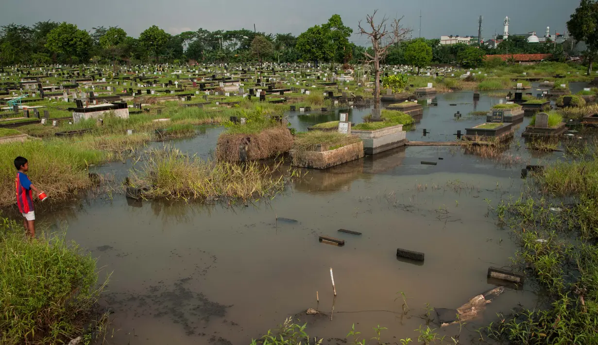 Seorang bocah bermain layang-layang diatas makam di Tempat Pemakaman Umum (TPU) Tanah Kusir, Jakarta, Selasa (25/4). (Liputan6.com/Gempur M. Surya)