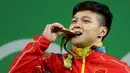 Lifter Tiongkok, Long Qingquan menggigit medali emas yang diraihnya pada Olimpiade Rio 2016 di Rio de Janeiro, Brasil, Minggu (7/8). Long mencetak rekor pada cabang angkat besi kelas 56 kg dengan total angkatan 307 kg. (REUTERS/Stoyan Nenov)