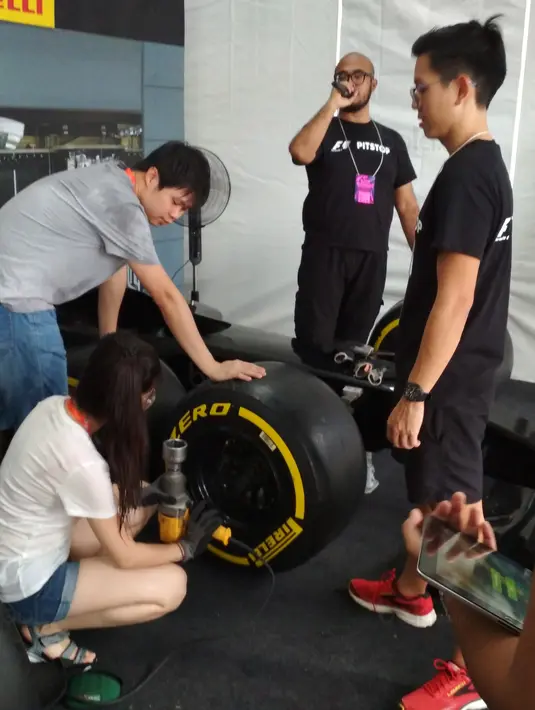 Sejumlah pengunjung belajar membersihkan ban mobil F1 di pit stop challenge pada ajang F1 GP Singapura, (17/9/2017). Kegiatan ini untuk menarik warga mengenal tentang F1. (Bola.com/Wirawan Kusuma)