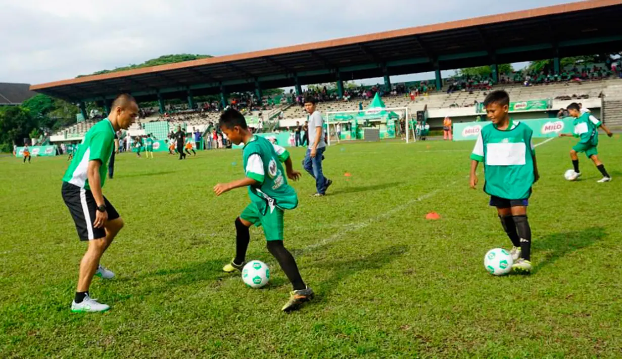 Kurniawan Dwi Yulianto (kiri) memberikan football clinic kepada anak-anak usia sekolah dasar di stadion Mini Universitas Sumut, Minggu (14/2/2016). Football clinic merupakan salah satu kegiatan di MILO Football Championship 2016. (Foto:Istimewa)