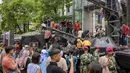 Beberapa anak terlihat senang ketika menaiki kendaraan tempur yang dipamerkan. Tampak dalam foto, warga berfoto bersama kendaraan militer selama Pameran Marinir Indonesia, yang menandai peringatan Hari Ulang Tahun ke-80 Korps Marinir TNI AL di Surabaya, Jawa Timur pada Minggu 9 November 2025. (JUNI KRISWANTO/AFP)