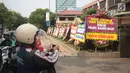 Warga mengabadikan karangan bunga di Halaman Polres Jakarta Barat, Jumat (23/11). Puluhan karangan bunga yang dikirimkan warga tersebut diberikan guna mendukung kepolisian dalam memberantas aksi premanisme di Jakarta Barat. (Liputan6.com/Faizal Fanani)