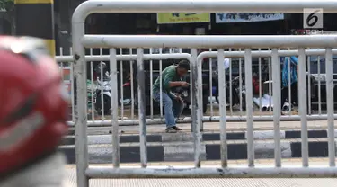 Seorang pria menerobos pagar pembatas jalan di kawasan Pasar Minggu, Jakarta, Kamis (5/4). Kondisi Jembatan Penyeberangan Orang (JPO) yang tak kunjung diperbaiki membuat warga nekat menyeberang lewat celah pagar pembatas. (Liputan6.com/Immanuel Antonius)