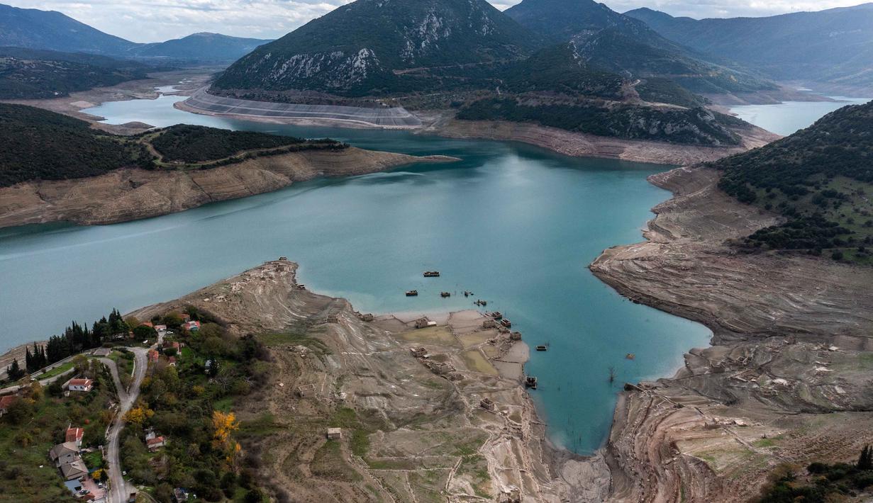 Foto ini menunjukkan sisa-sisa rumah yang muncul kembali ketika permukaan danau buatan Mornos menurun akibat kekeringan, di desa Kallio, sekitar 240 km barat laut Athena, Yunani pada 3 November 2025. Sebuah desa yang sudah tenggelam muncul kembali di Danau Mornos, Yunani pada 3 November 2025. (Angelos TZORTZINIS/AFP)