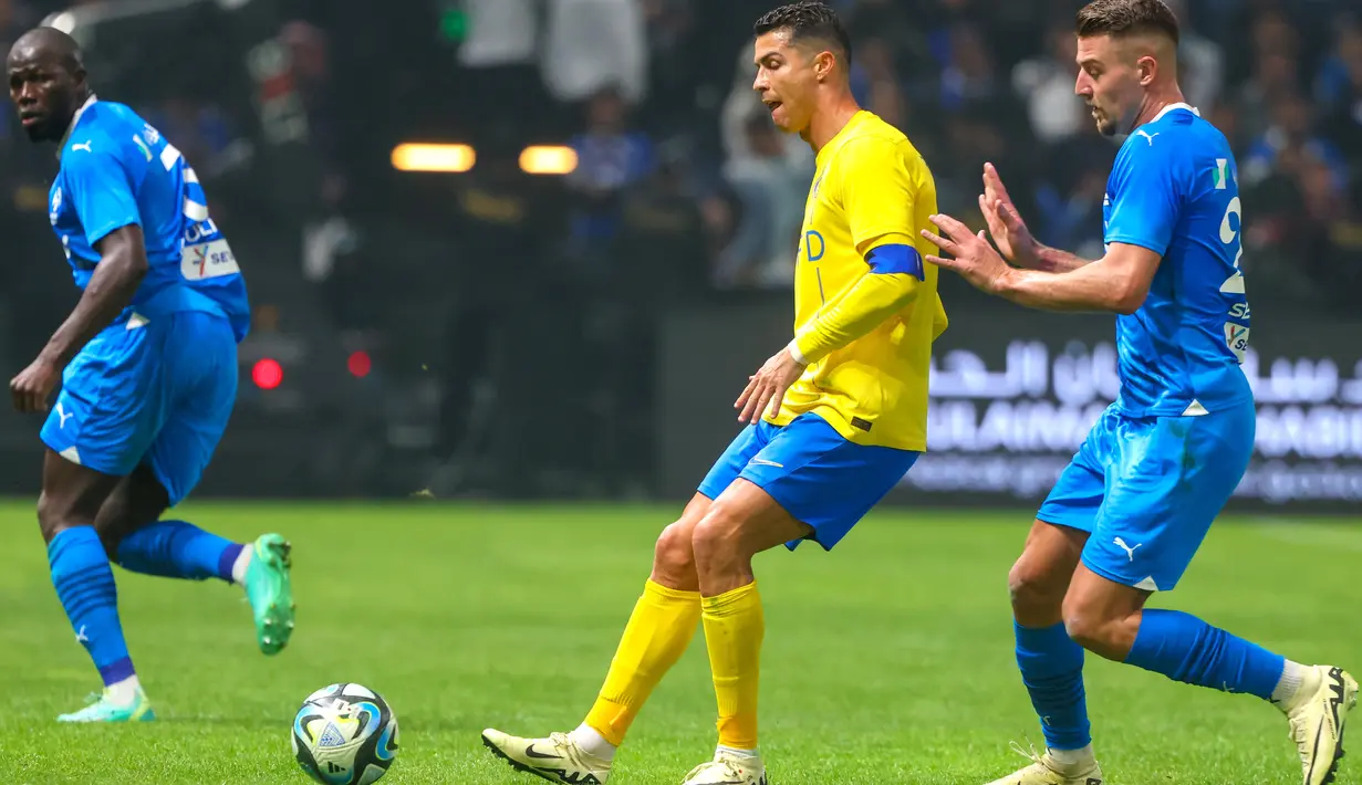 Pemain Al-Nassr, Cristiano Ronaldo, dijaga pemain Al-Hilal,  Sergej Milinkovic-Savic, pada laga persahabatan di Kingdom Arena, Riyadh, Jumat (9/2/2024). (AFP/Fayez Nureldine)