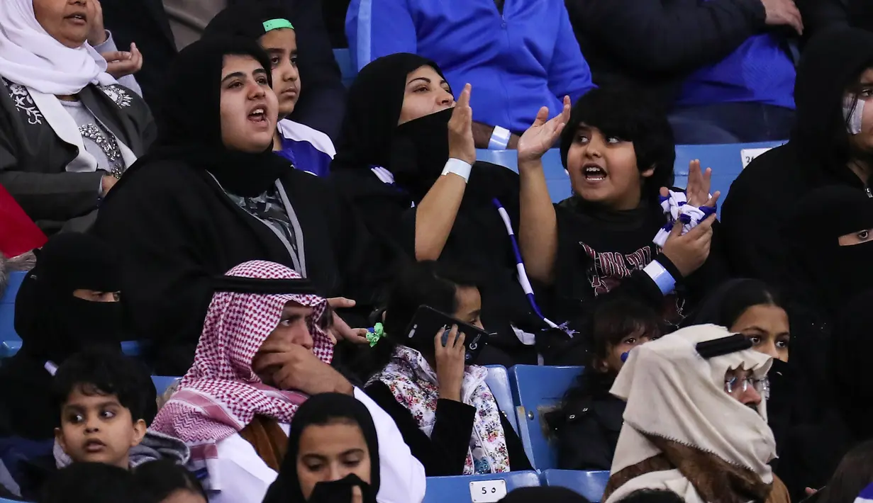 Seorang wanita mendukung tim Al-Hilal dari Saudi saat melawan Al-Ittihad dalam pertandingan Liga Saudi Pro di King Fahd International Stadium di Riyadh (13/1). (AFP Photo/Ali Al-Arifi)