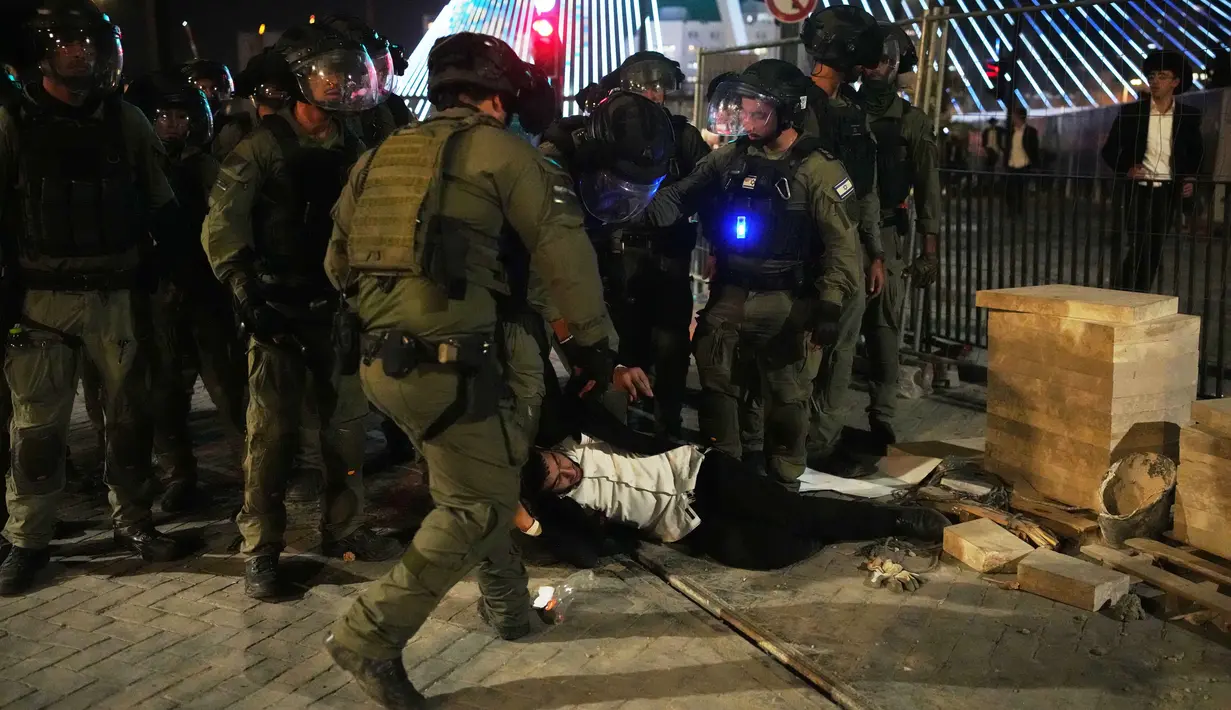 Petugas polisi Israel membubarkan pria Yahudi ultra-Ortodoks yang menghalangi jalan dalam aksi protes menentang rencana wajib militer mereka di militer Israel, di Yerusalem, Kamis 30 Oktober 2025. Sebelumnya, puluhan ribu pria ultra-Ortodoks memenuhi pintu masuk ke Yerusalem dalam lautan hitam pada Kamis (30/10/2025) untuk memprotes rencana wajib militer bagi mereka. (AP Photo/Ohad Zwigenberg)