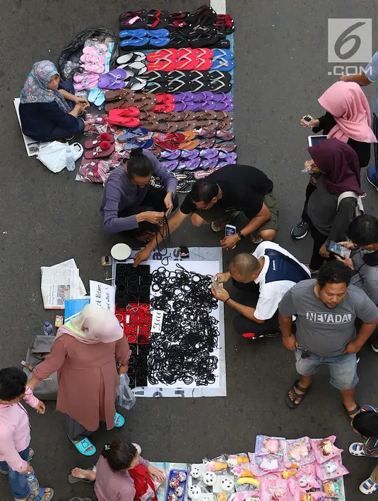 Pengunjung memilih barang saat pelaksanaan car free day di sepanjang Jalan Sudirman, Jakarta, Minggu (1/7). Kurangnya pengawasan menyebabkan banyak PKL yang berjualan tidak pada tempatnya dan memenuhi area CFD. (Liputan6.com/Immanuel Antonius)