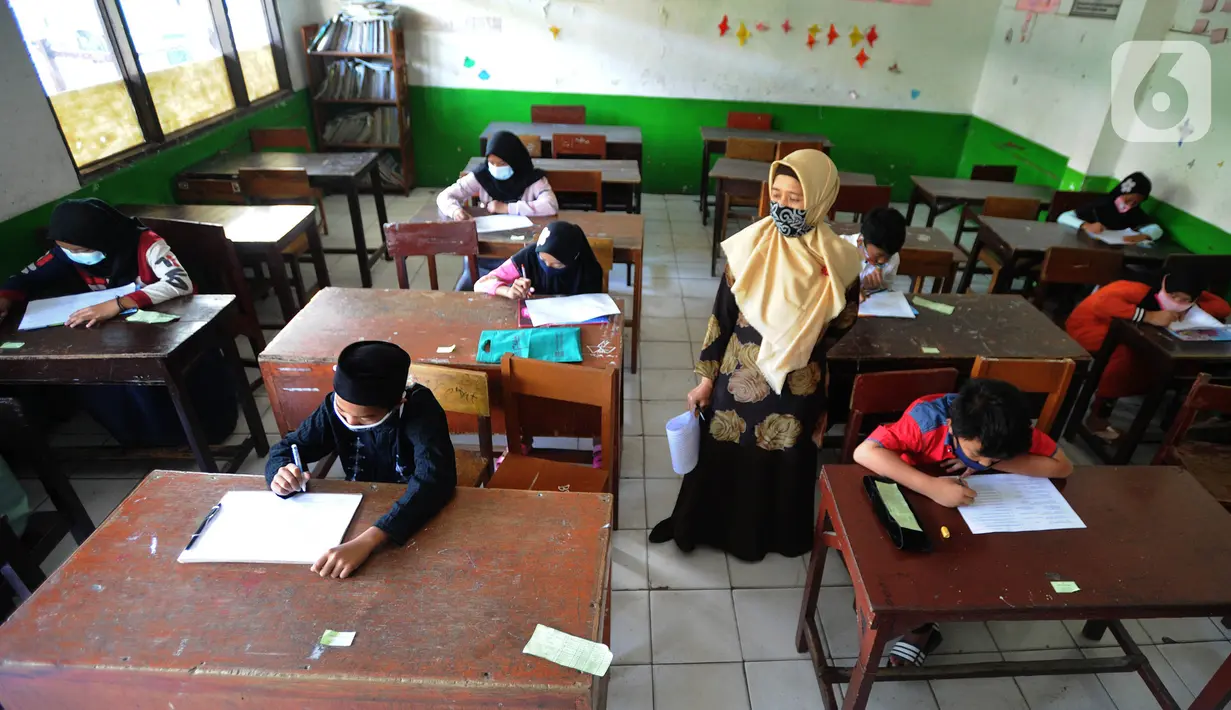 Guru mengawasi murid kelas V saat menjalani ujian Penilaian Akhir Semester (PAS) tahun pelajaran 2020/2021 di Madrasah Ibtidayah (MI) Assu'ada di Pancoran Mas, Depok, Jawa Barat, Selasa (1/12/2020). Ujian dilaksanakan dengan menerapkan protokol kesehatan dalam kelas. (merdeka.com/Arie Basuki)