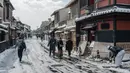 Orang-orang melintasi Jalan Hanamikoji setelah salju tebal dan angin kencang semalaman mempengaruhi wilayah luas negara itu di Kyoto, Jepang, Rabu (25/1/2023). Karena pola musim dingin yang keras diperkirakan akan berlangsung hingga Kamis (26/1), beberapa daerah di Jepang dapat mengalami suhu terendah dalam satu dekade. (Fred Mery / AFP)