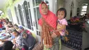 Seorang wanita menggendong anaknya saat beristirahat bersama  pengungsi bencana tsunami di sebuah masjid di Tenjolahang, provinsi Banten, Rabu (26/12). Saat ini tercatat ada 16.082 orang  mengungsi selepas tsunami Selat Sunda. (Sonny TUMBELAKA / AFP)