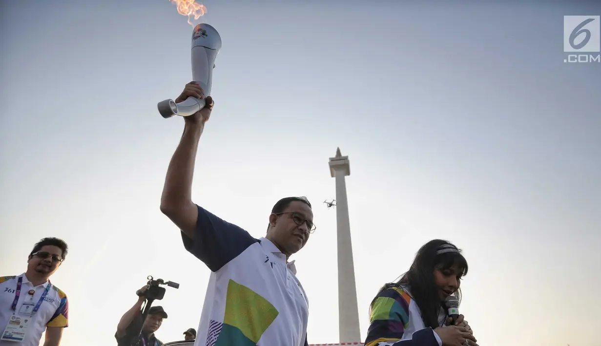 Gubernur DKI Jakarta Anies Baswedan berlari membawa obor Asian Games 2018 di Jakarta, Sabtu (18/8). Rute lari obor Asian Games 2018 kali ini dari Monas menuju Balai Kota DKI Jakarta kemudian dilanjutkan menuju ke GBK. (Liputan6.com/Faizal Fanani)