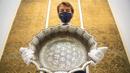 Karyawan rumah lelang Sotheby memegang baskom bergigi perak abad ke-12 dengan desain astrologi, diperkirakan berharga 1.000.000-1.500.000 poundsterling, sebagai bagian dari penjualan Arts of the Islamic World dan India pada 31 Maret di London, Inggris, Senin (29/3/2021). (Dominic Lipinski/PA via AP)