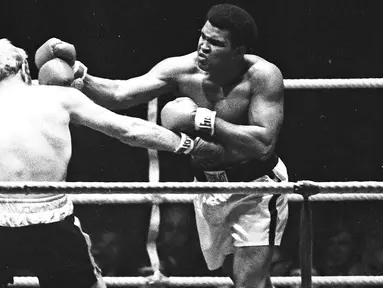 Muhammad Ali saat menghantam Richard Dunn dengan pukulan keras dalam turnamen WBC & WBA kelas berat di Munich, Jerman, (24/5/1976). Ali wafat pada usia 74 tahun dan dimakamkan di kota kelahirannya di Louisville, Kentucky. (REUTERS/Action Images/MSI)