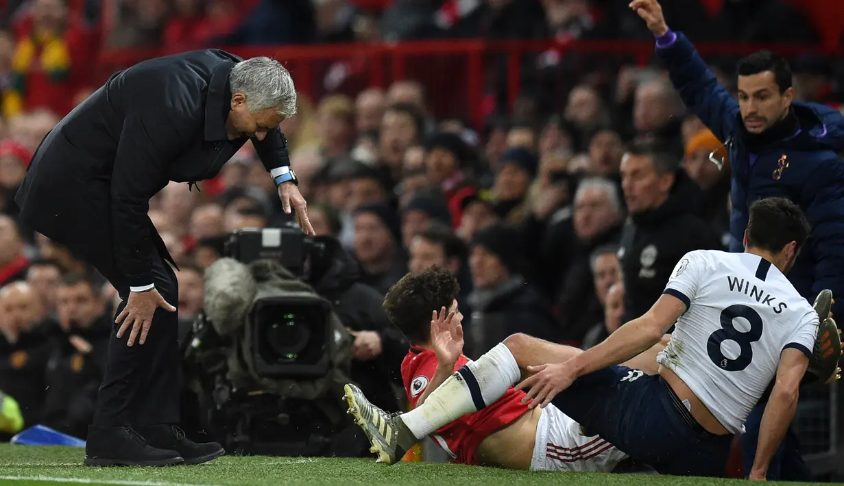 Pelatih Jose Mourinho kesakitan saat tertendang pemain Tottenham Hotspur, Harry Winks dan pemain Manchester United, Daniel James pada pertandingan lanjutan Liga Inggris di Old Trafford, Rabu (4/12/2019). Tottenham kalah tipis atas MU 2-1. (AFP Photo/Oli Scarff)