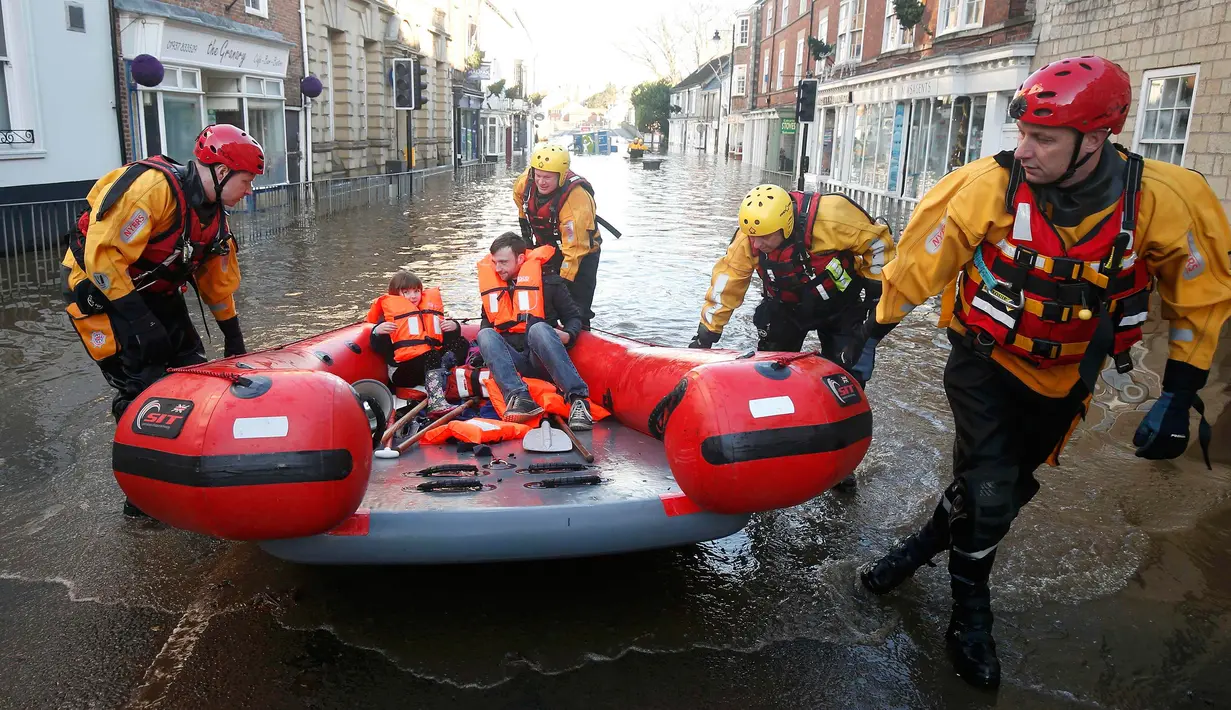 Tim regu penyelamat menyisir lokasi pemukiman warga yang terendam banjir menggunakan perahu karet di Tadcaster, Inggris utara, Minggu (27/12). Banjir akibat luapan sungai Ouse yang telah memperburuk sejumlah wilayah Inggris utara. (REUTERS/Andrew Yates)