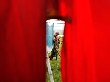 Seorang dhobi atau tukang cuci menggantungkan kain untuk dikeringkan setelah dicuci di tepian Sungai Gomti di Lucknow, India, 12 September 2020. Dhobi adalah pekerja binatu tradisional yang mencuci pakaian dengan tangan dan menjemurnya di bawah sinar matahari. (AP Photo/Rajesh Kumar Singh)
