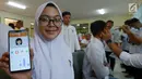 Siswi SMKN 2 Gambir menunjukkan aplikasi E-Skrining pada handphonenya saat dokter Puskesmas melakukan pemeriksaan kesehatan di sekolahnya, Jakarta, Jumat (30/8/2019). Malalui aplikasi ini para siswa dapat lebih mudah mengetahui riwayat sakit mereka setelah diperiksa dokter. (merdeka.com/Imam Buhori)