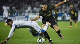 Pemain Paris Saint-Germain (PSG), Kylian Mbappe, berebut bola dengan pemain AJ Auxerre, Rayan Raveloson, pada laga Liga Prancis, di Stade de I’Abbe Deschamps, Senin (22/5/2023). PSG menang dengan skor tipis 2-1. (AFP/Julien De Rosa)