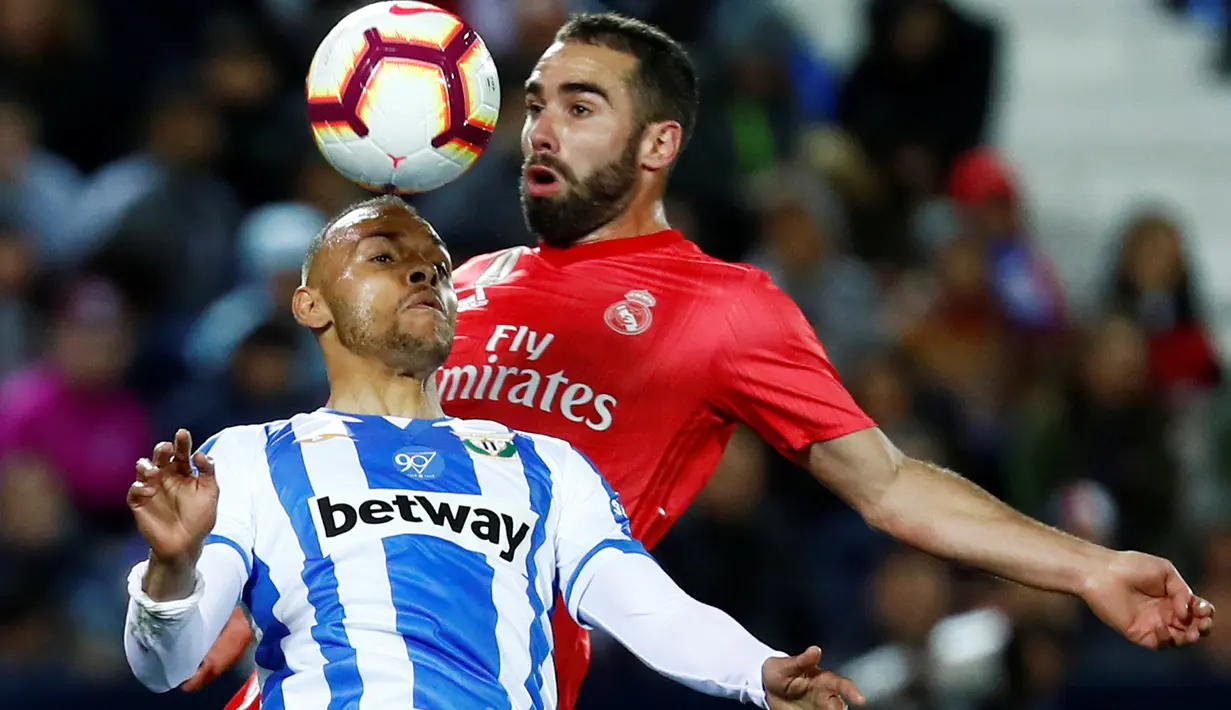 Bek Real Madrid Dani Carvajal berebut bola dengan  pemain Leganes, Martin Braithwaite dalam lanjutan La Liga 2018-2019 di Estadio Municipal Butarque, Senin (15/4). Real Madrid hanya mampu meraih hasil imbang 1-1 saat bertandang ke markas Leganes. (REUTERS/Juan Medina)