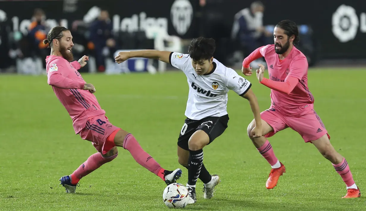 Gelandang Valencia, Lee Kang-in mengontrol bola dibayangi pemain Real Madrid pada lanjutan La Liga di Stadion Mestalla, Selasa (9/11/2020) dinihari WIB. Real Madrid kalah telak 1-4 dari tuan rumah Valencia. (AP Photo/Alberto Saiz)