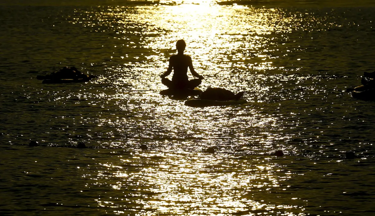 Seorang wanita berbikini berlatih yoga Float Metta dengan papan seluncur di Laut Adriatic, Kroasia, Kamis (6/8/2015). (REUTERS/Pawel Kopczynski)