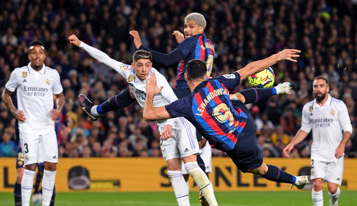 Pemain Barcelona, Robert Lewandowski berusaha mencetak gol ke gawang Real Madrid pada laga pekan ke-26 Liga Spanyol 2022/2023 di Camp Nou, Barcelona, Senin (20/03/2023). Blaugrana menang dengan skor 2-1 pada pertandingan yang bertajuk El Classico tersebut. (AFP/Lluis Gene)