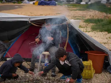 Anak-anak pengungsi yang melarikan diri bersama keluarga mereka dari serangan artileri Israel di Lebanon selatan membuat api unggun di samping tenda yang digunakan sebagai tempat berlindung di Beirut, Lebanon, Rabu, 1 April 2026. Di tengah meningkatnya serangan udara Israel, gelombang pengungsi di Lebanon terus bertambah. (AP Photo/Emilio Morenatti)