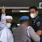 Rizieq Shihab (tengah) melambaikan tangan sesaat sebelum masuk gedung utama Mapolda Metro Jaya, Jakarta, Sabtu (12/12/2020). Rizieq Shihab akan menjalani pemeriksan sebagai tersangka penghasutan dan kerumunan di tengah pandemi Covid-19. (Liputan6.com/Helmi Fithriansyah)